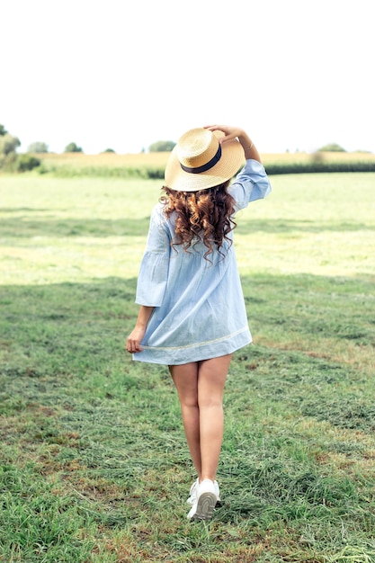 Mujer hermosa joven está caminando en el parque. Verano. Una niña camina en la primavera. Campo. Cálido.