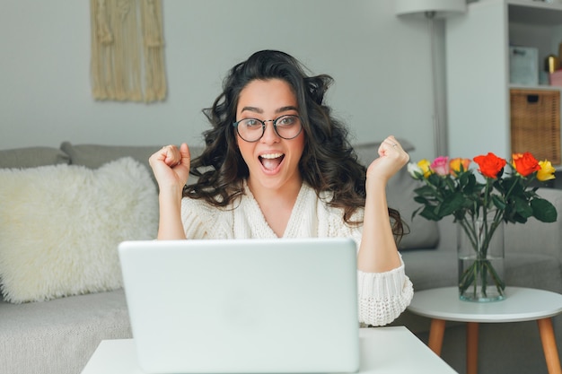 La mujer hermosa joven está comprando en línea. Trabajando en Internet. Oficina en casa. COVID-19.