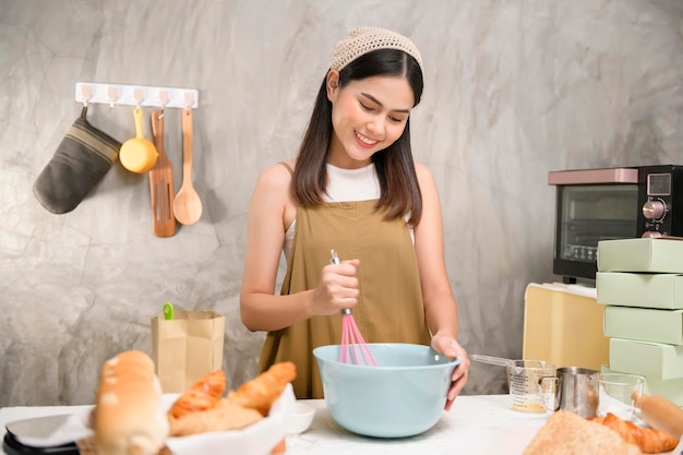 Mujer hermosa joven está horneando en su negocio de panadería y cafetería de cocina