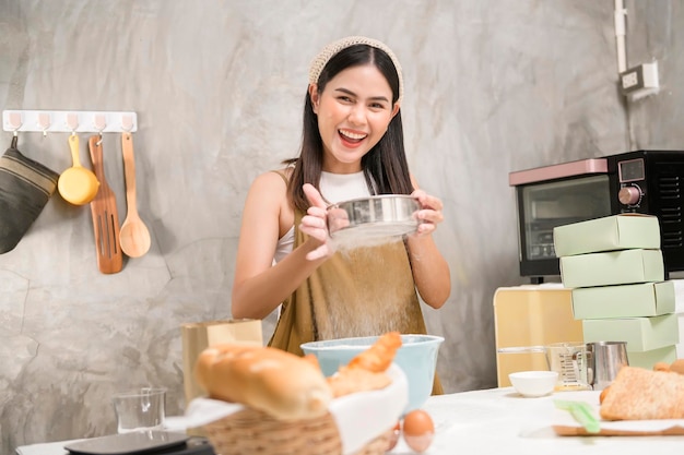 Mujer hermosa joven está horneando en su negocio de panadería y cafetería de cocina