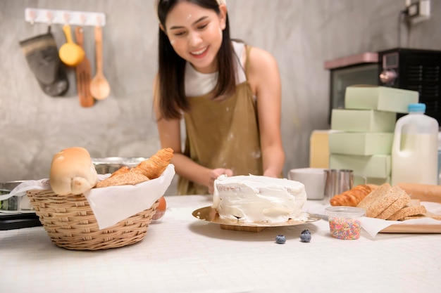 Mujer hermosa joven está horneando en su negocio de panadería y cafetería de cocina