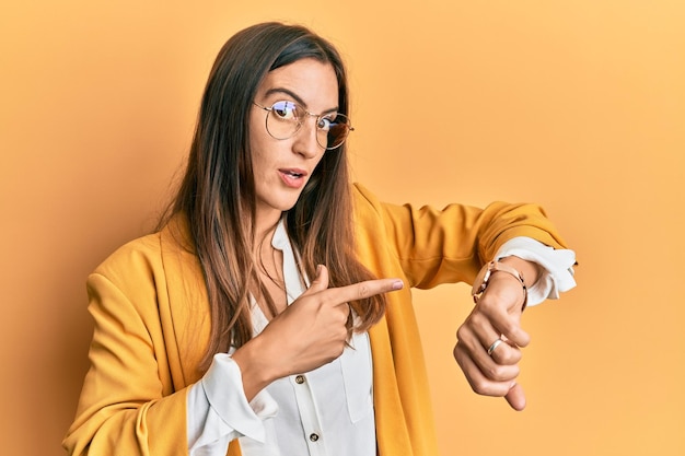 Foto mujer hermosa joven con estilo de negocios y anteojos con prisa apuntando a ver la impaciencia del tiempo molesta y enojada por el retraso de la fecha límite