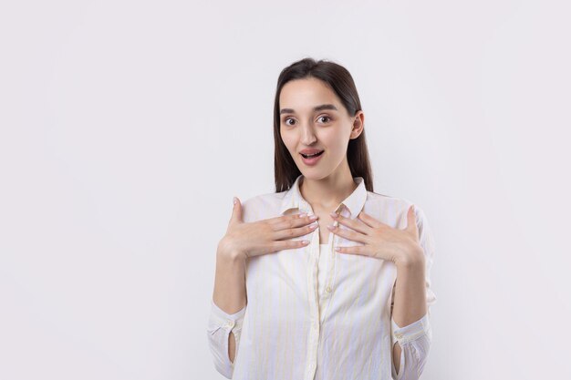 Mujer hermosa joven con expresión facial de sorpresa de pie sobre fondo blanco.