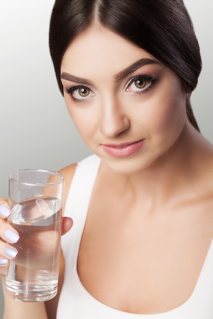 Mujer hermosa joven feliz bebiendo agua