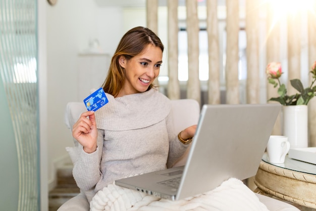 Mujer hermosa joven feliz por encontrar artículos de compra a la venta en línea. Hermosa chica con ordenador portátil para compras en línea en casa