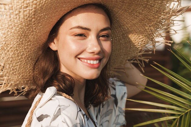 una mujer hermosa joven feliz positiva optimista complacida en la playa caminando en una hermosa mañana soleada sobre plantas tropicales.