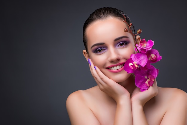 Foto mujer hermosa joven con la flor de la orquídea