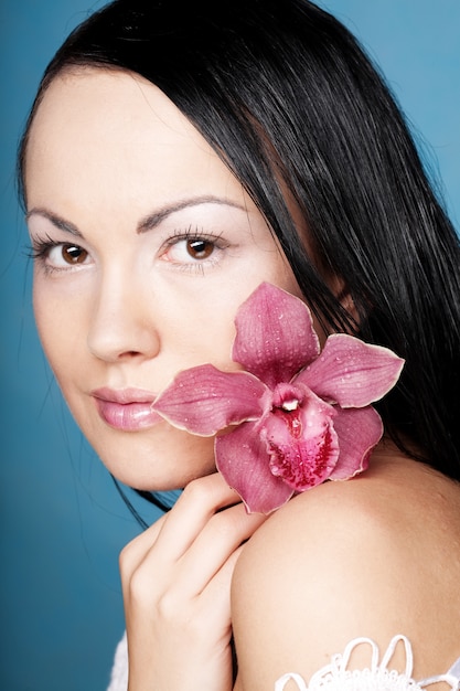 Mujer hermosa joven con flor rosa