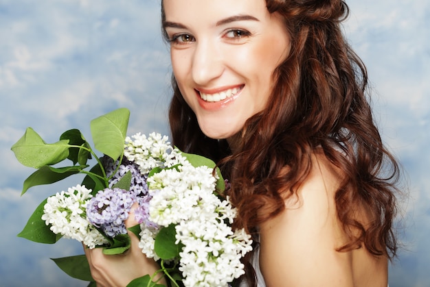 Mujer hermosa joven con flores lilas