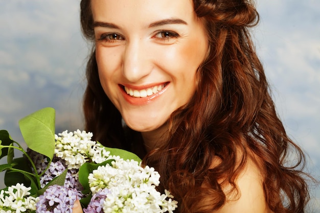 Mujer hermosa joven con flores lilas