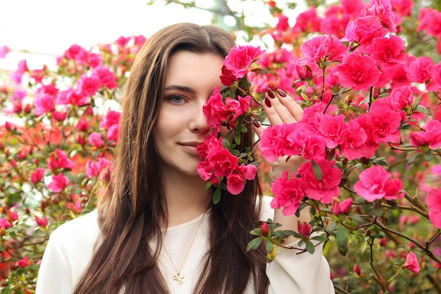 Mujer hermosa joven entre flores rosadas