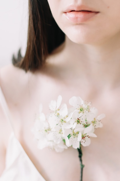 Mujer hermosa joven con flores sobre la superficie blanca