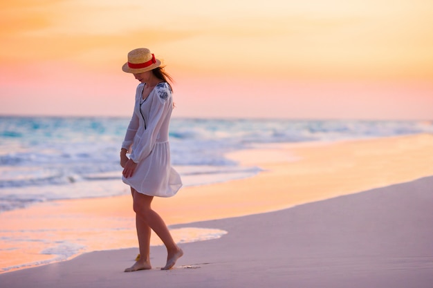 Mujer hermosa joven en el fondo del atardecer del océano