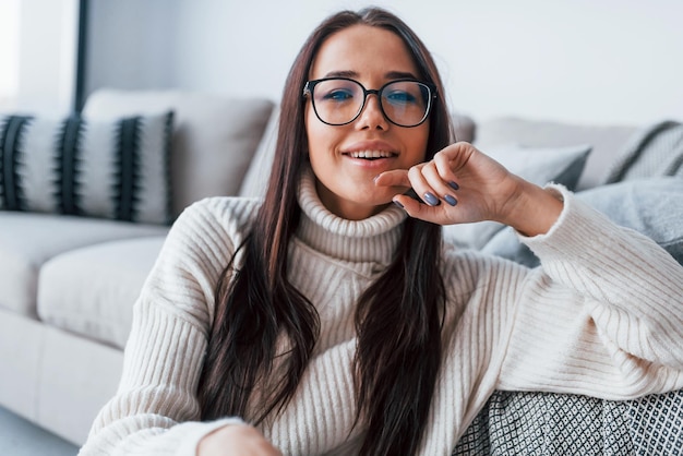 Mujer hermosa joven con gafas sentada sola en casa.