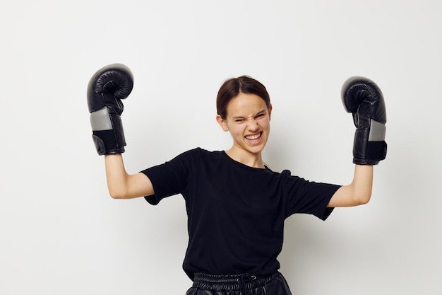 Mujer hermosa joven en guantes de boxeo en pantalones negros y un fondo claro de camiseta