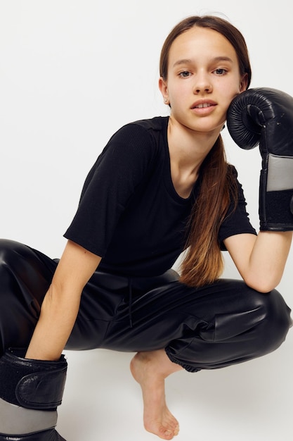 Mujer hermosa joven en guantes de boxeo en el suelo en entrenamiento de fitness de camiseta negra