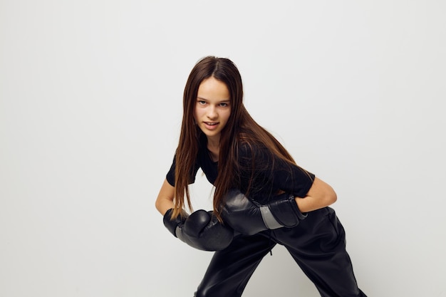 Mujer hermosa joven en guantes de boxeo uniformes deportivos negros posando fondo aislado