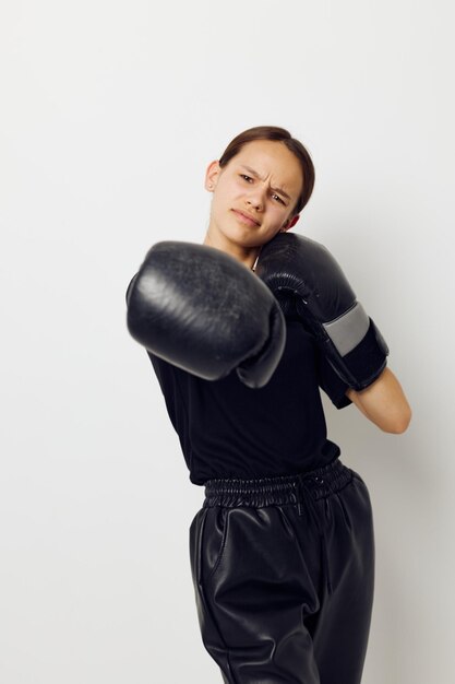 Mujer hermosa joven en guantes de boxeo uniformes deportivos negros posando fondo aislado