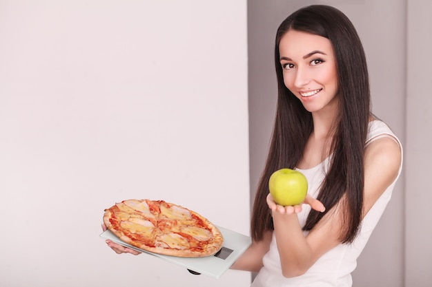 Mujer hermosa joven hace una elección entre un estilo de vida saludable y alimentos nocivos