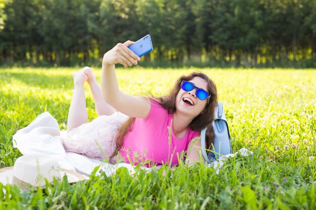 Mujer hermosa joven hacer foto selfie en smartphone en un picnic en el verano.