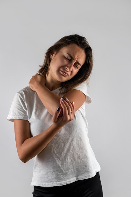 Foto mujer hermosa joven haciendo muecas con dolor de codo aislado sobre fondo blanco.