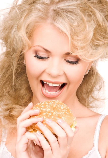 Mujer hermosa joven con hamburguesa sobre pared blanca