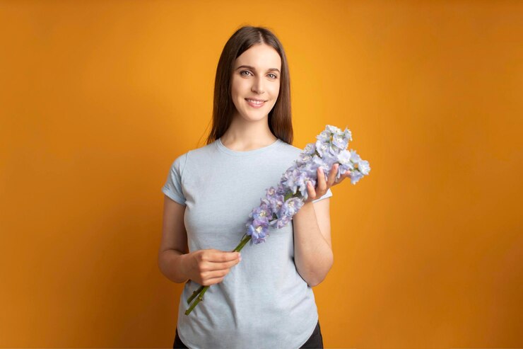 Mujer hermosa joven con un hermoso ramo de flores azules en las manos Delphinium Flowers