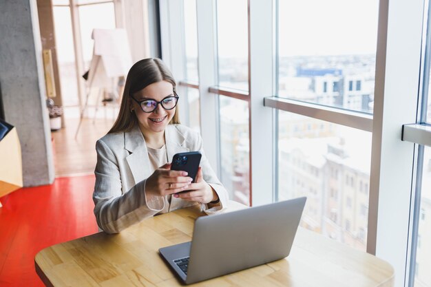 Foto mujer hermosa joven hombre de negocios usa teléfono inteligente para negocios compras en línea transferencia de dinero finanzas banca por internet mujer que trabaja en un café