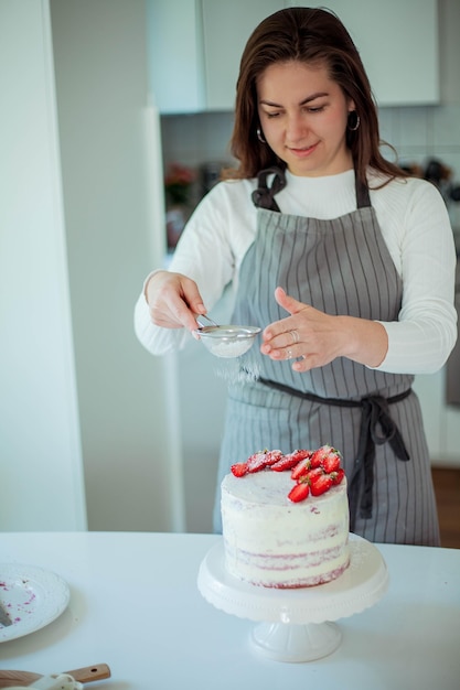 Mujer hermosa joven hornea un pastel. Dulces Confitería.