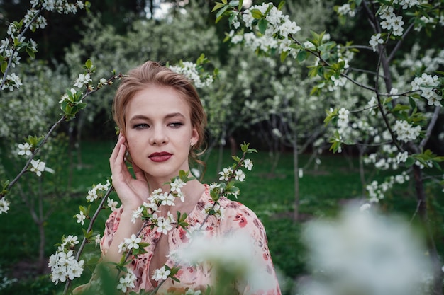 Mujer hermosa joven en el jardín de cerezos en flor.