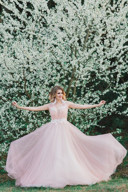 Mujer hermosa joven en jardín floreciente. Novia, en, vestido de novia