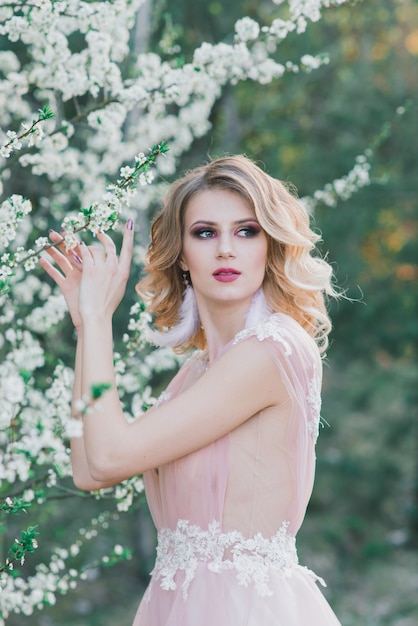 Mujer hermosa joven en jardín floreciente. Novia.