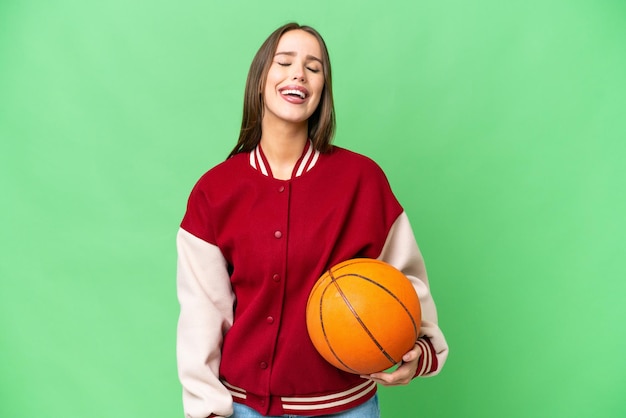 Mujer hermosa joven jugando baloncesto sobre fondo clave de croma aislado riendo