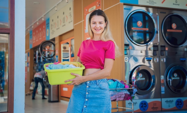 Mujer hermosa joven lava y seca la ropa en la lavandería