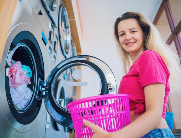 Foto mujer hermosa joven lava y seca la ropa en la lavandería