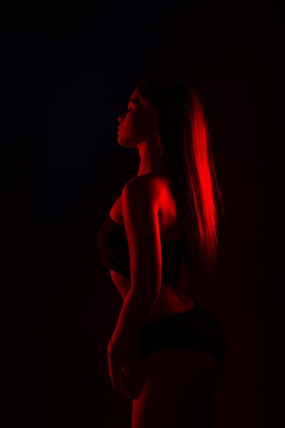 Mujer hermosa joven en lencería posando en luz de fondo roja