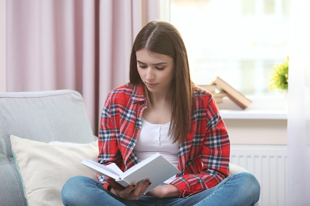 Mujer hermosa joven leyendo un libro en casa