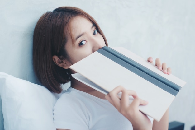 Mujer hermosa joven en el libro de lectura de la ropa interior blanca en la cama