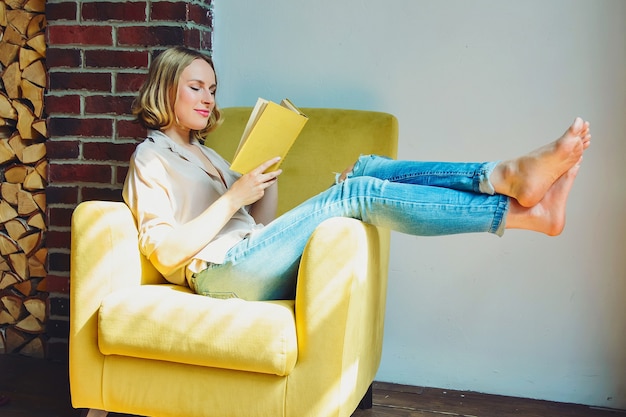 Mujer hermosa joven con un libro en la silla