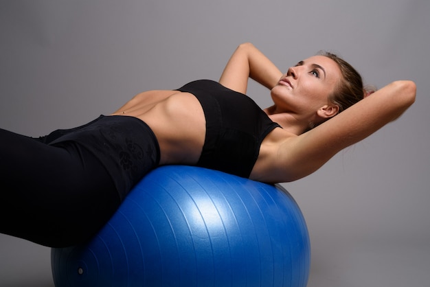 Mujer hermosa joven lista para el gimnasio contra la pared gris