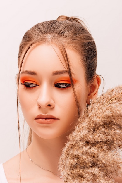 Mujer hermosa joven con maquillaje creativo y flores secas