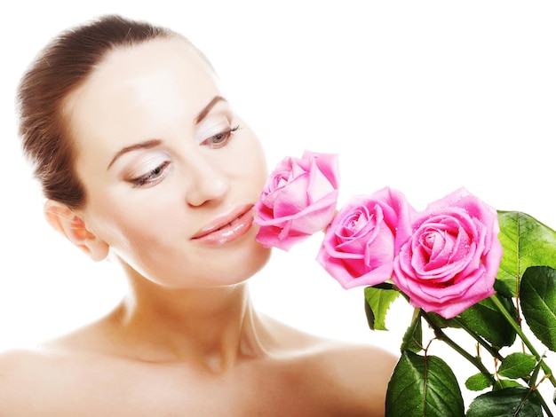 Mujer hermosa joven con maquillaje fresco y hermosa flor rosa sobre fondo blanco.