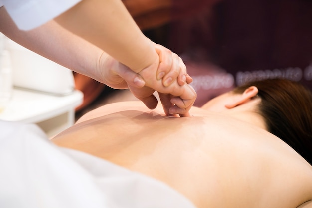 Mujer hermosa joven con masaje de espalda en el salón de spa.