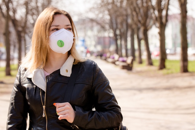 Mujer hermosa joven en una máscara protectora al aire libre