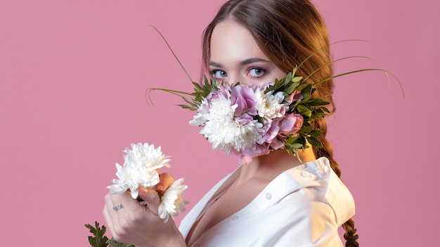 Mujer hermosa joven en una mascarilla de flores