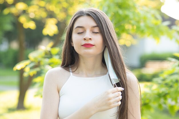 Mujer hermosa joven con una mascarilla en el parque