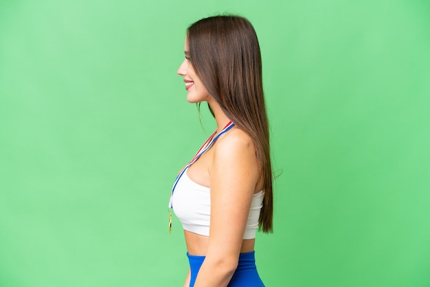 Mujer hermosa joven con medallas sobre fondo clave de croma aislado con expresión feliz