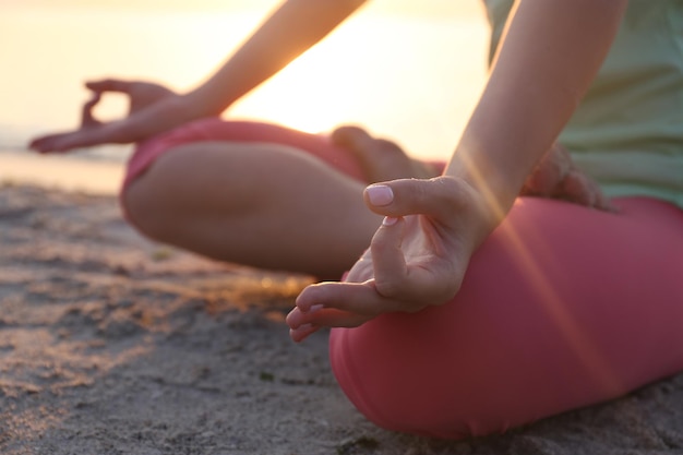 Mujer hermosa joven meditando yoga en la playa de cerca