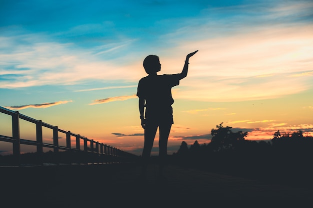 Mujer hermosa joven mira esperanzada en sus manos al atardecer.Concepto de éxito en la mano