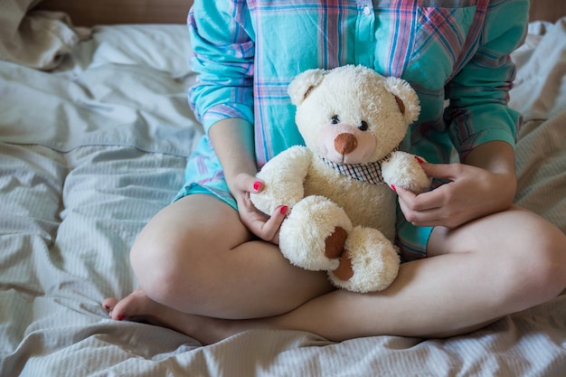 Mujer hermosa joven con osito de peluche en la cama